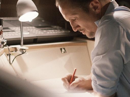 Szene aus dem Kinofilm "Der blinde Fleck": Benno Fürmann alias Ulrich Chaussy sitzt an einem Tisch und schreibt.