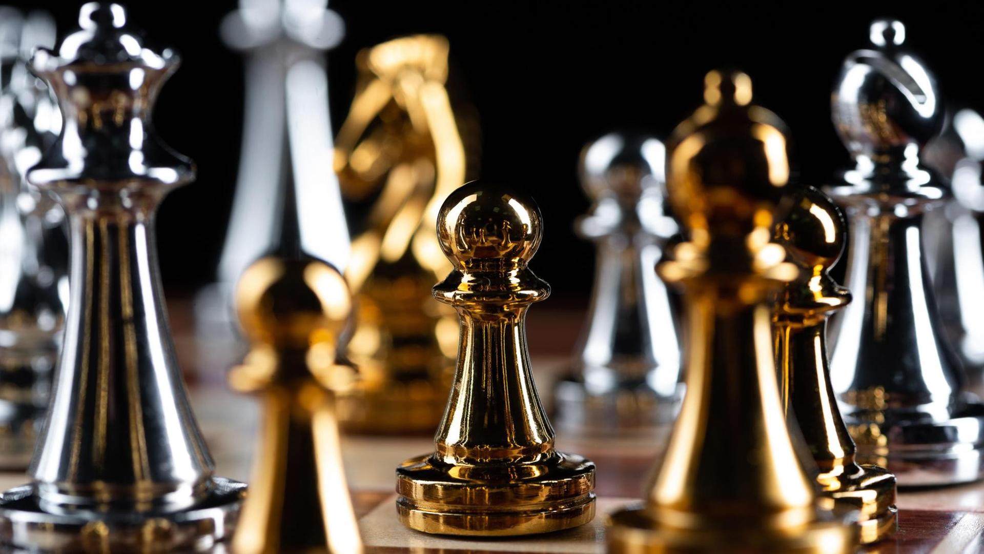 Nahaufnahme von goldenen und silbernen Schachfiguren auf einem Schachbrett.