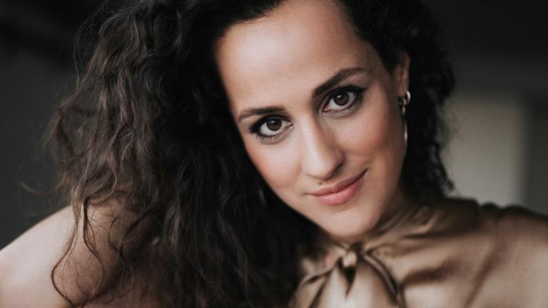 Porträt der Sängerin Marie Seidler mit offenem, braunen, welligem Haar, in hellbrauner Schluppenbluse.