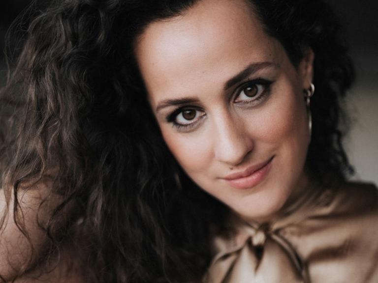 Porträt der Sängerin Marie Seidler mit offenem, braunen, welligem Haar, in hellbrauner Schluppenbluse.