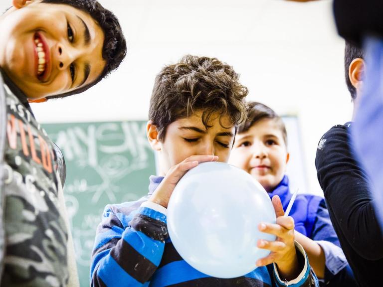 Die Physikerin und Paedagogin Jessica Oertel und der ehrenamtlichen Helfer Krystof Beuermann experimentieren mit Kindern aus der Fluechtlingsunterkunft. (2017)
