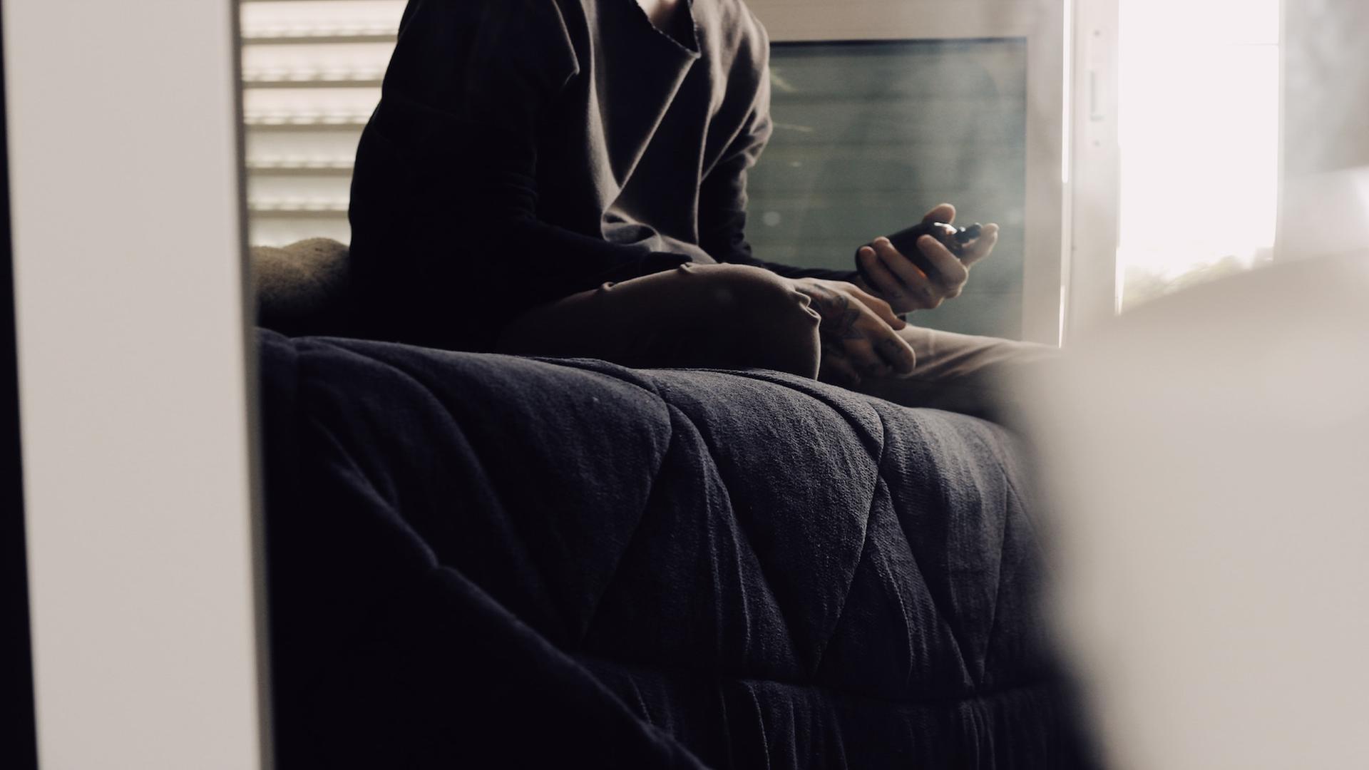 Ein Mann sitzt verträumt auf seinem Bett und sprüht Parfüm in die Luft. Ein Mann sitzt verträumt auf seinem Bett und sprüht Parfüm in die Luft.