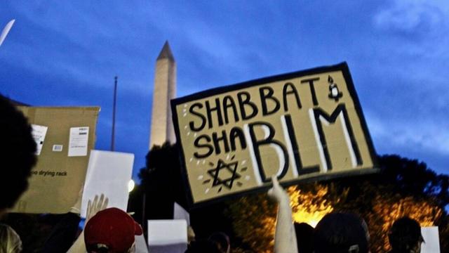 Auf einer Demonstration von Black Lives Matter in Washington DC wird ein Schild in die Höhe gehalten. Die Aufschrift lautet: "Shabbat Sha BLM".
