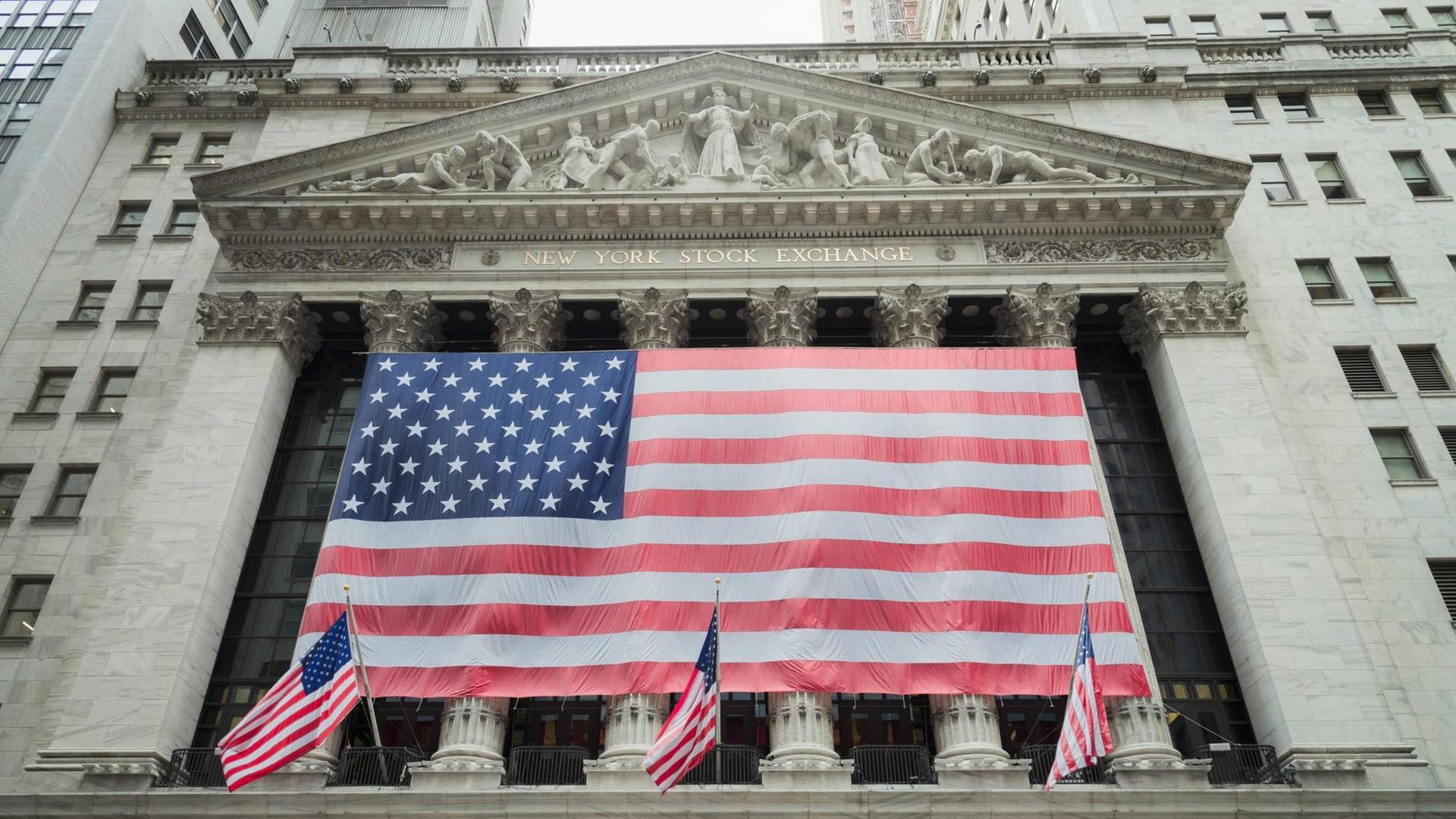 Sie sehen eine US-amerikanische Flagge vor der Börse in New York City Sie sehen eine US-amerikanische Flagge vor der Börse in New York City