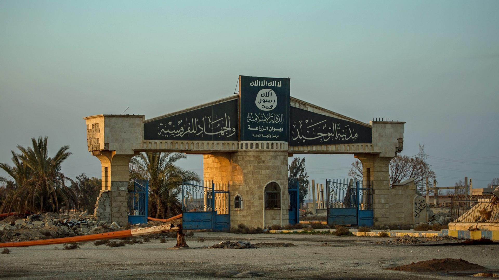 Auf einer Toreinfahrt eines zerbombten Areals in der Region um Rakka in Syrien ist das Logo der vertriebenen Terrormiliz Islamischer Staat zu sehen. Auf einer Toreinfahrt eines zerbombten Areals in der Region um Rakka in Syrien ist das Logo der vertriebenen Terrormiliz Islamischer Staat zu sehen.
