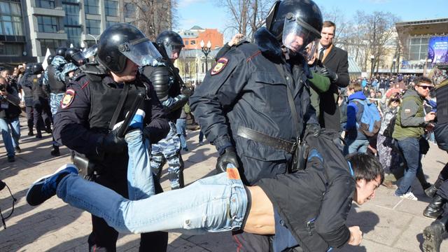 Ein Polizist trägt einen Demonstranten weg.