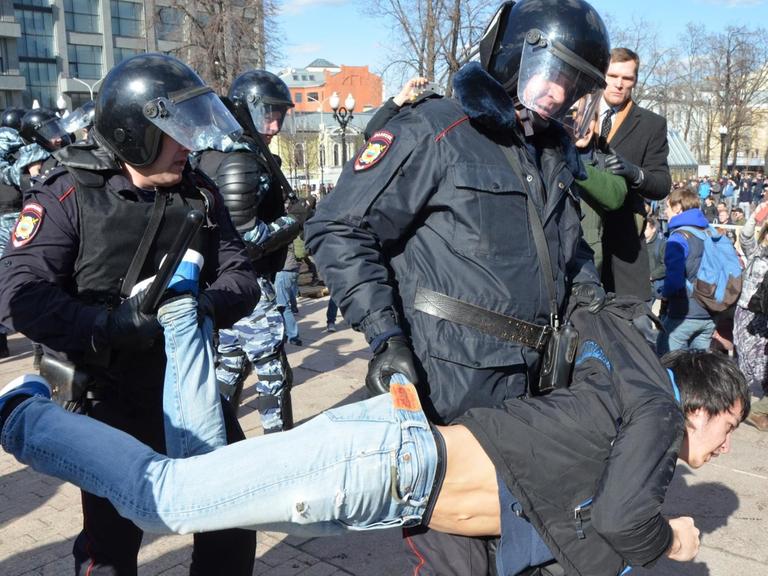 Ein Polizist trägt einen Demonstranten weg.