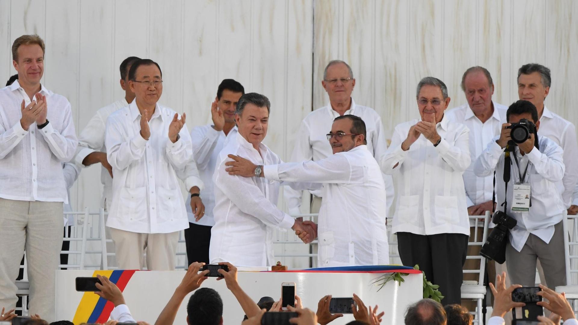 Der kolumbianische Präsident Juan Manuel Santos und der Kommandeur der FARC-Guerrilla-Organisation Timoleon Jimenez, alias Timochenko, geben sich beim Festakt in Cartagena die Hand. Der kolumbianische Präsident Juan Manuel Santos und der Kommandeur der FARC-Guerrilla-Organisation Timoleon Jimenez, alias Timochenko, geben sich beim Festakt in Cartagena die Hand.