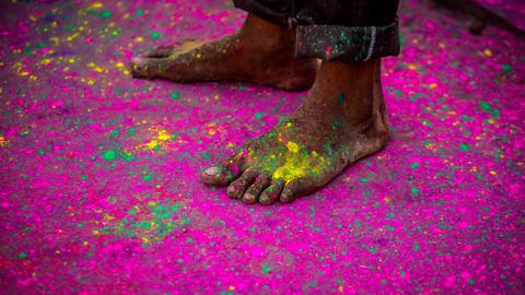 Die bloßen Füße eines Mannes inmitten vieler Farbpigmente