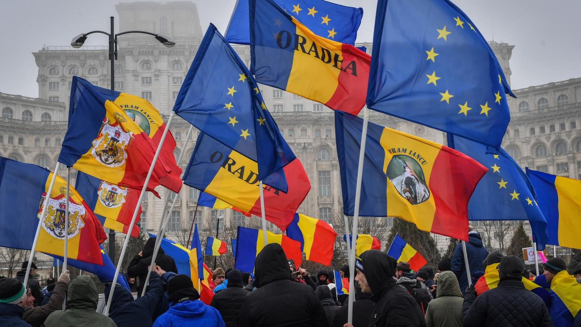 Demonstranten mit rumänischen und EU-Flaggen vor dem Parlament in Bukarest | Photo by Daniel Mihailescu / AFP Demonstranten mit rumänischen und EU-Flaggen vor dem Parlament in Bukarest | Photo by Daniel Mihailescu / AFP