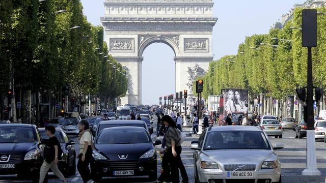 Autos sthen vor einer Kreuzung auf dem Champs d'Elysee in Paris, Im Hintergrund der Arc de Triomphe.