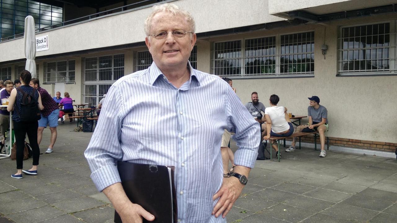 Claudio Offenberg steht vor einem Stadion, im Hintergrund tummeln sich einige Fans. Claudio Offenberg steht vor einem Stadion, im Hintergrund tummeln sich einige Fans.