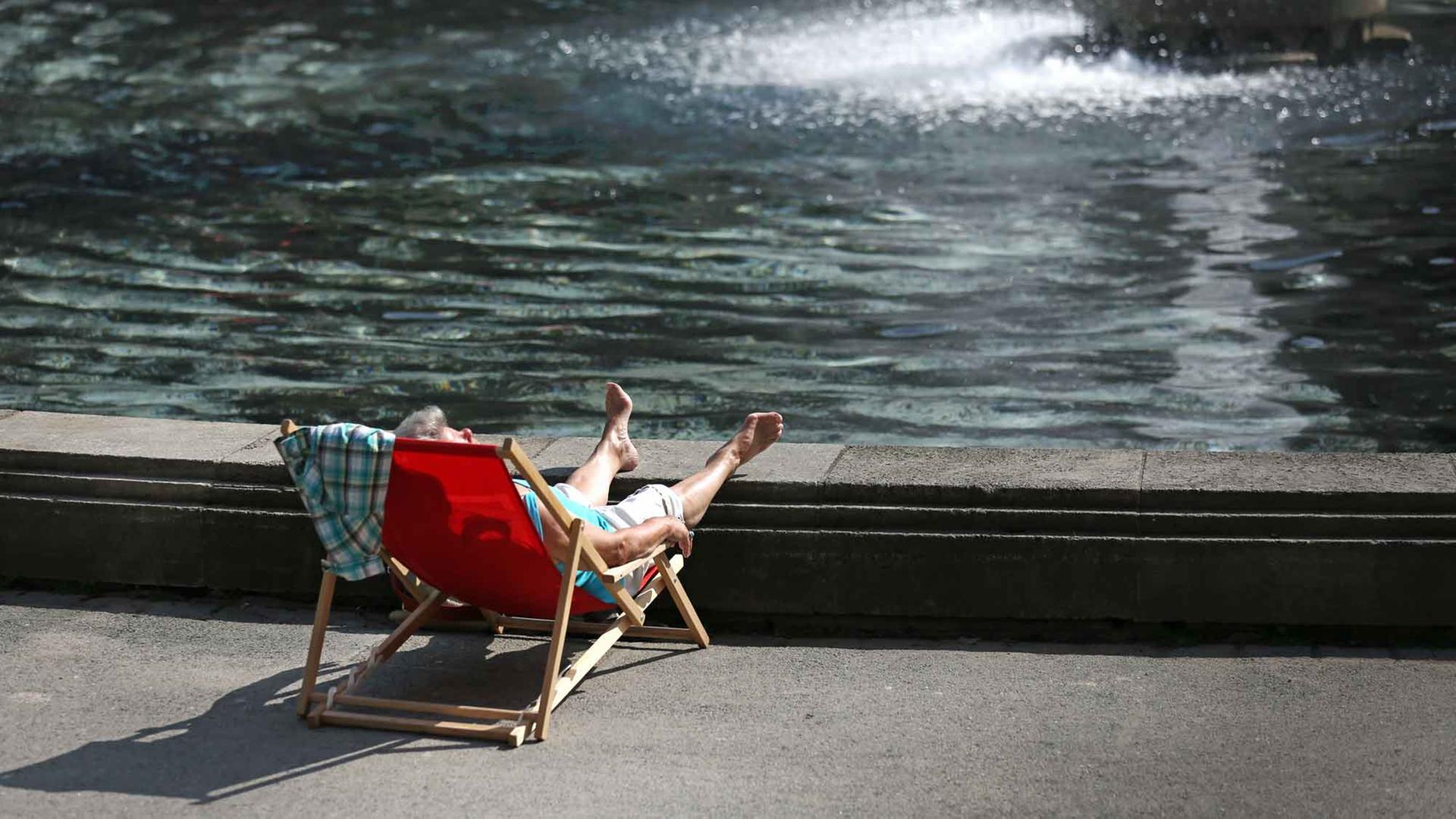 Eine Frau sonnt sich in einem Liegestuhl am Springbrunnen des Museum Kunstpalast in Düsseldorf Eine Frau sonnt sich in einem Liegestuhl am Springbrunnen des Museum Kunstpalast in Düsseldorf