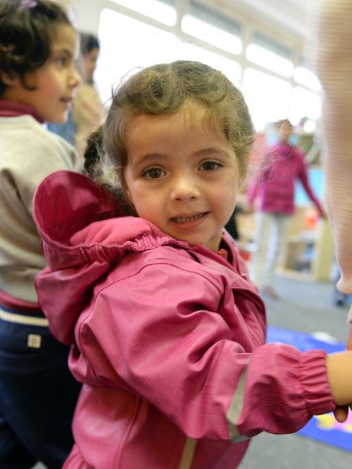 Asylbewerberkind Alma aus Syrien steht am 18.11.2014 im Kindergarten der Erstaufnahmestelle für Flüchtlinge in Meßstetten (Baden-Württemberg) mit anderen Flüchtlingskindern im Kreis, um einen Geburtstag zu feiern.
