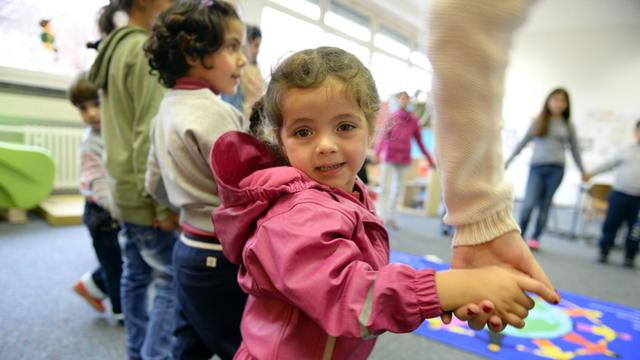 Asylbewerberkind Alma aus Syrien steht am 18.11.2014 im Kindergarten der Erstaufnahmestelle für Flüchtlinge in Meßstetten (Baden-Württemberg) mit anderen Flüchtlingskindern im Kreis, um einen Geburtstag zu feiern.
