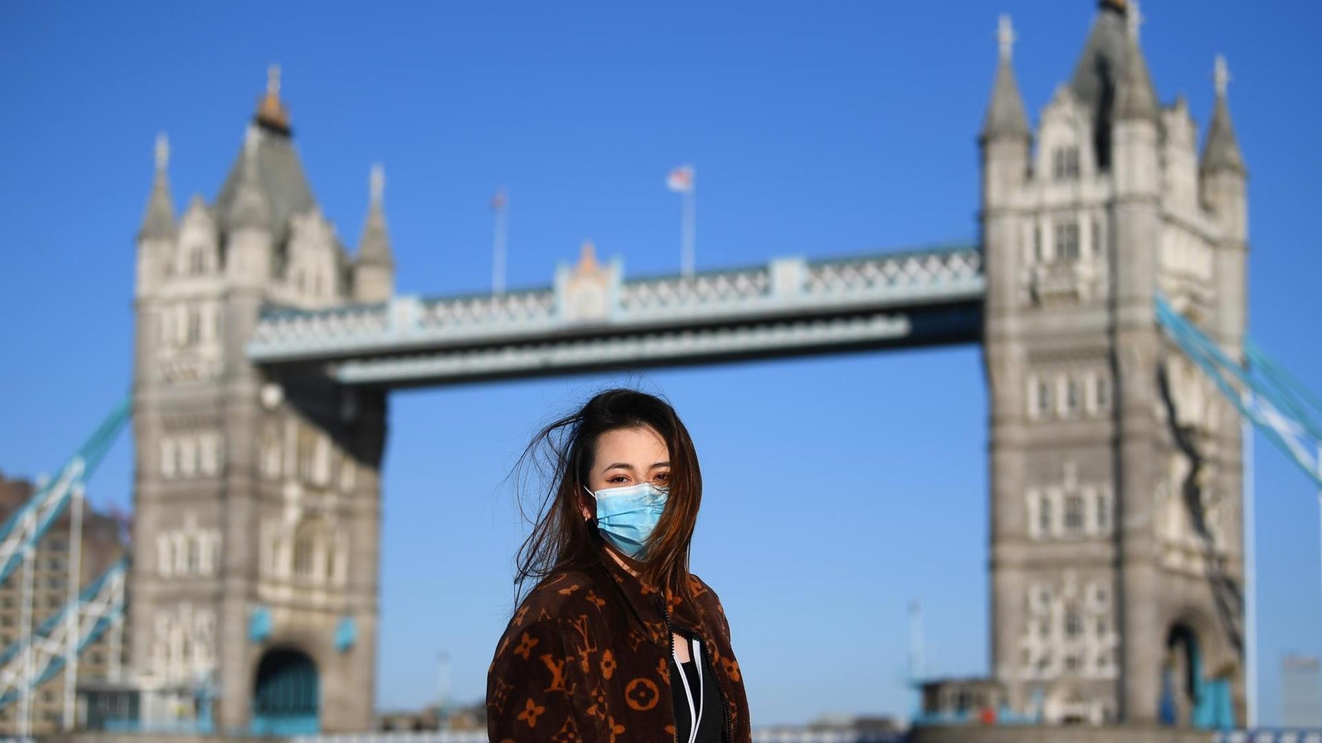 Ein Frau mit Maske posiert für ein Foto vor der Tower Bridge in London, England. Ein Frau mit Maske posiert für ein Foto vor der Tower Bridge in London, England.