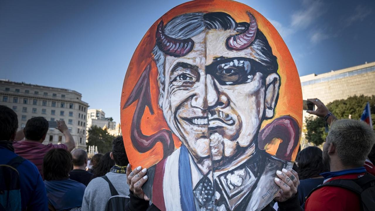 Ein Schild mit der Karikatur von Sebastian Piñera und dem Diktator Pinochet, während der Demonstration gegen die chilenische Regierung in Barcelona, Spanien.