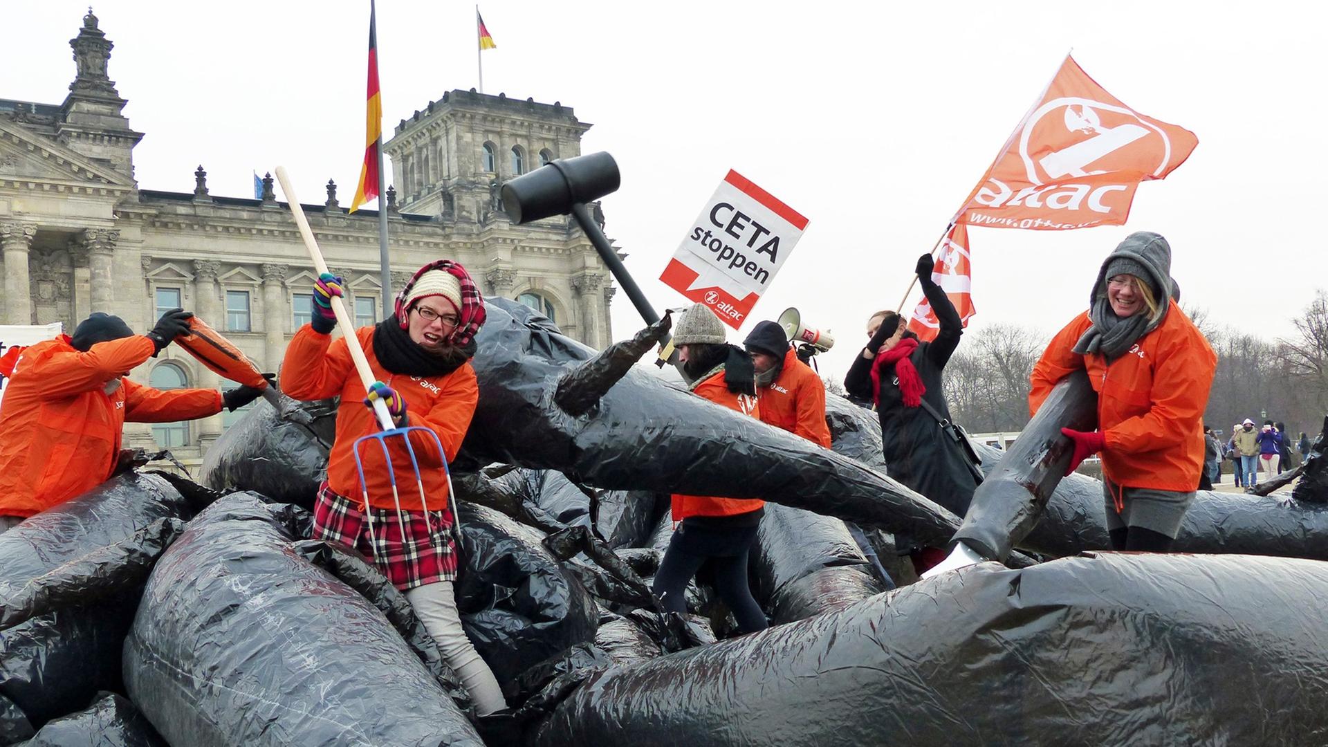Mehrere Aktivisten von Attac kämpfen vor dem Berliner Reichstagsgebäude mit einem Monster und halten Protestplakate. Mehrere Aktivisten von Attac kämpfen vor dem Berliner Reichstagsgebäude mit einem Monster und halten Protestplakate.