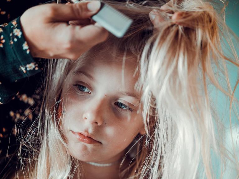 Eine Mutter kämmt ihrer Tochter die langen Haare.