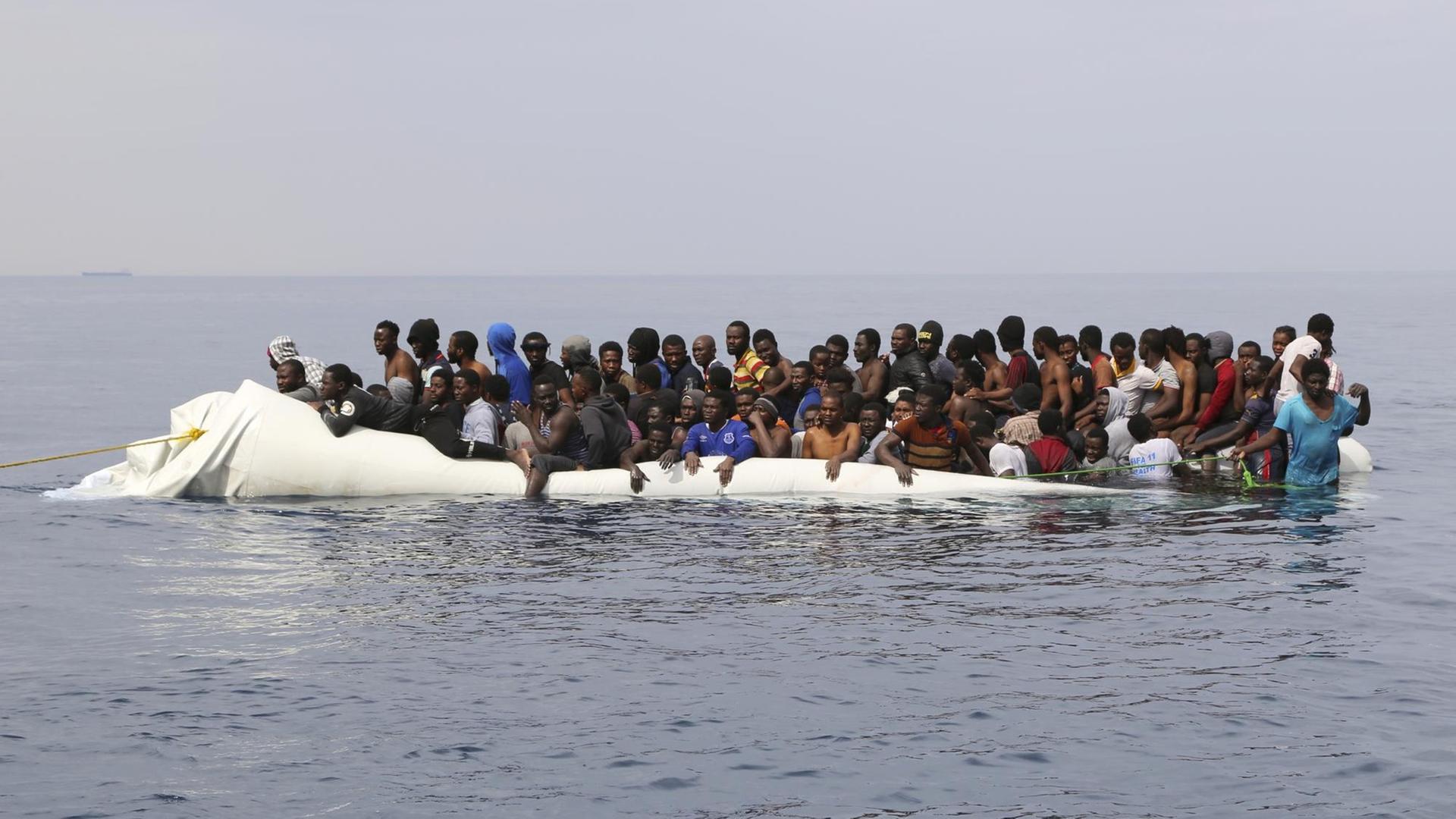 Flüchtlinge warten in einem überfüllten Schlauchboot vor der libyschen Küste auf ihre Rettung aus dem Mittelmeer.