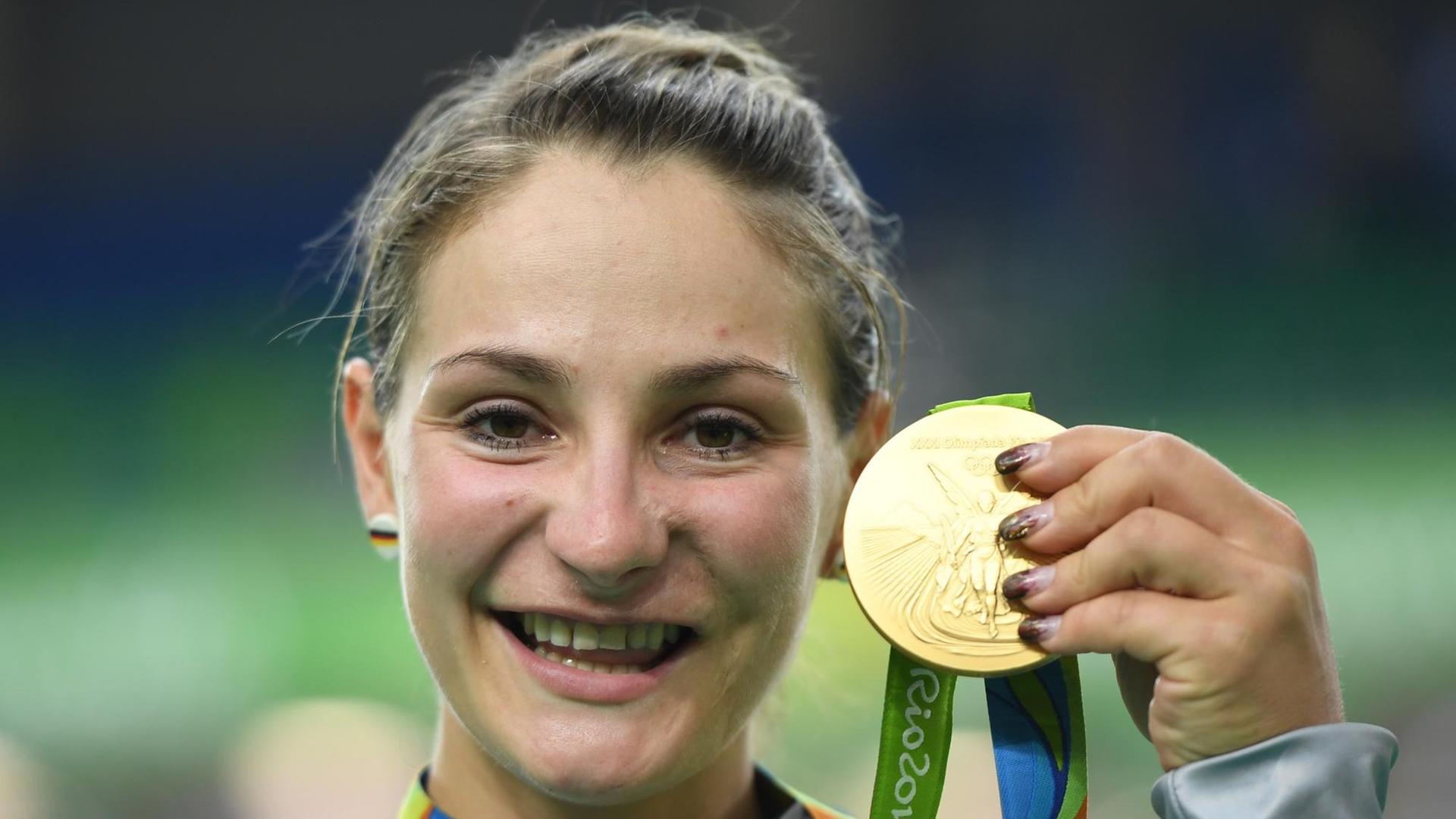 Vier Jahre nach ihrem überraschenden Olympiasieg im Teamsprint gewinnt Kristina Vogel wieder Gold - lächelnd hält sie die Medaille in die Kamera. Vier Jahre nach ihrem überraschenden Olympiasieg im Teamsprint gewinnt Kristina Vogel wieder Gold - lächelnd hält sie die Medaille in die Kamera.