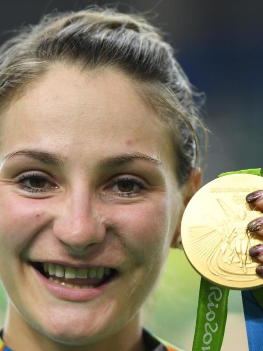 Vier Jahre nach ihrem überraschenden Olympiasieg im Teamsprint gewinnt Kristina Vogel wieder Gold - lächelnd hält sie die Medaille in die Kamera.