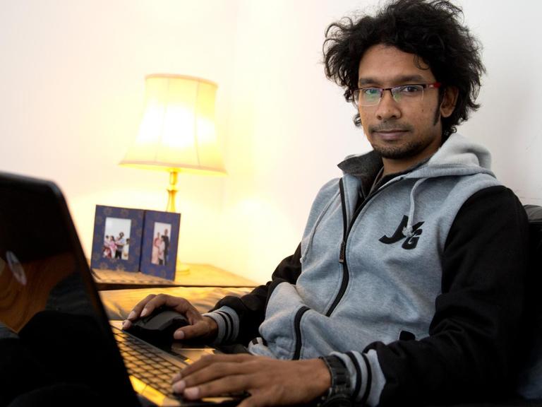 Der Blogger Ananya Azad aus Bangladesch sitzt in einer Wohnung in Hamburg an seinem Laptop.