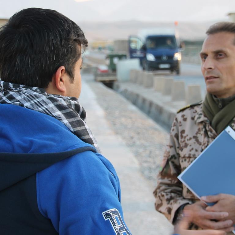 Afghanischer Helfer im Gespräch mit Bundeswehrangehörigem.