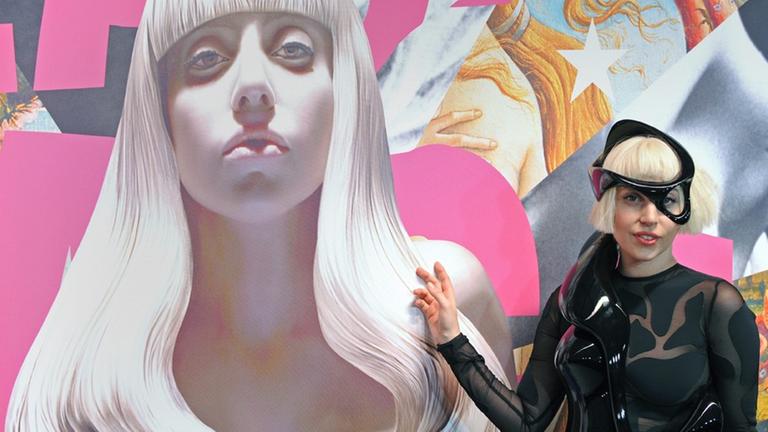 Die Musikerin Lady Gaga posiert in einem schwarzen Lederkostüm neben einem Bildnis von ihr, das der Künstler Jeff Koons angefertigt hat. Die Musikerin Lady Gaga posiert in einem schwarzen Lederkostüm neben einem Bildnis von ihr, das der Künstler Jeff Koons angefertigt hat.
