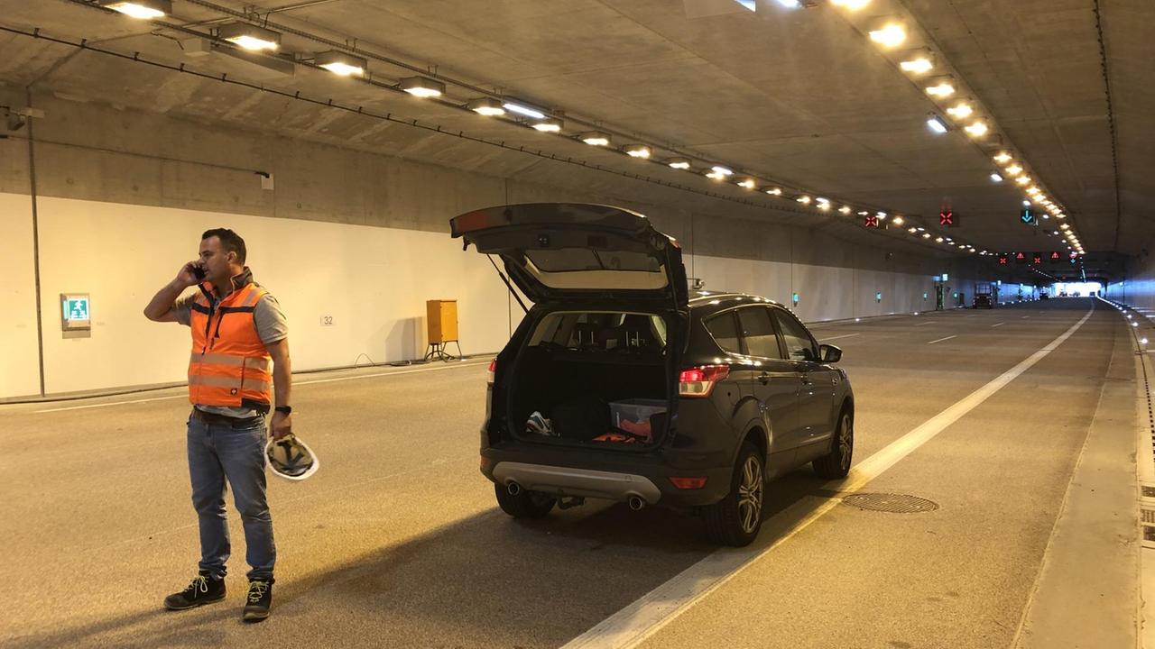 Ein Mann steht mit Warnweste vor seinem Auto im noch unbefahrenem Abschnitt mit Autobahndeckel. Ein Mann steht mit Warnweste vor seinem Auto im noch unbefahrenem Abschnitt mit Autobahndeckel.