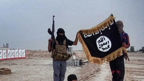 Isis-Kämpfer mit Maschinengewehren posieren mit der schwarzen Flagge der Gruppe für ein Foto