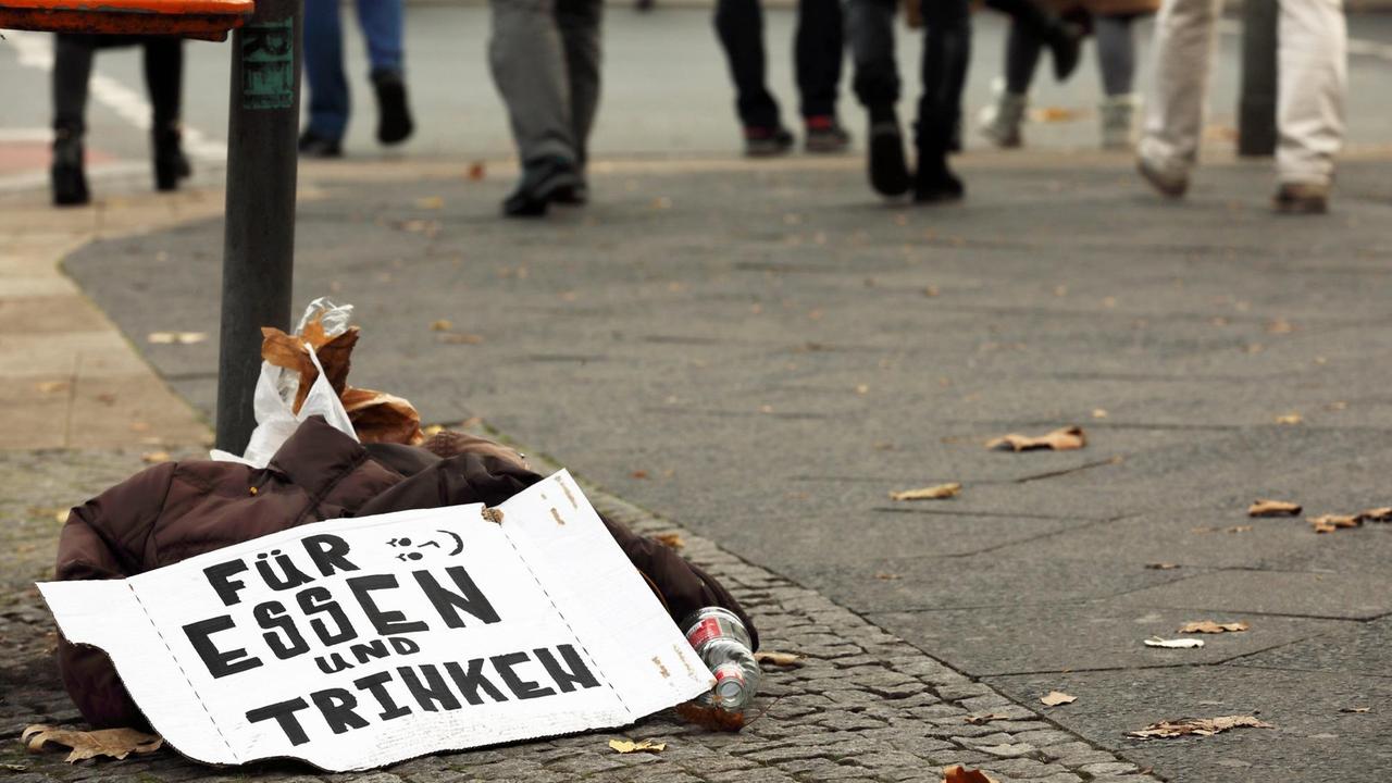 Zurückgelassenes Schild mit der Bitte um eine Spende für Essen und Trinke auf einer Straße in Berlin.