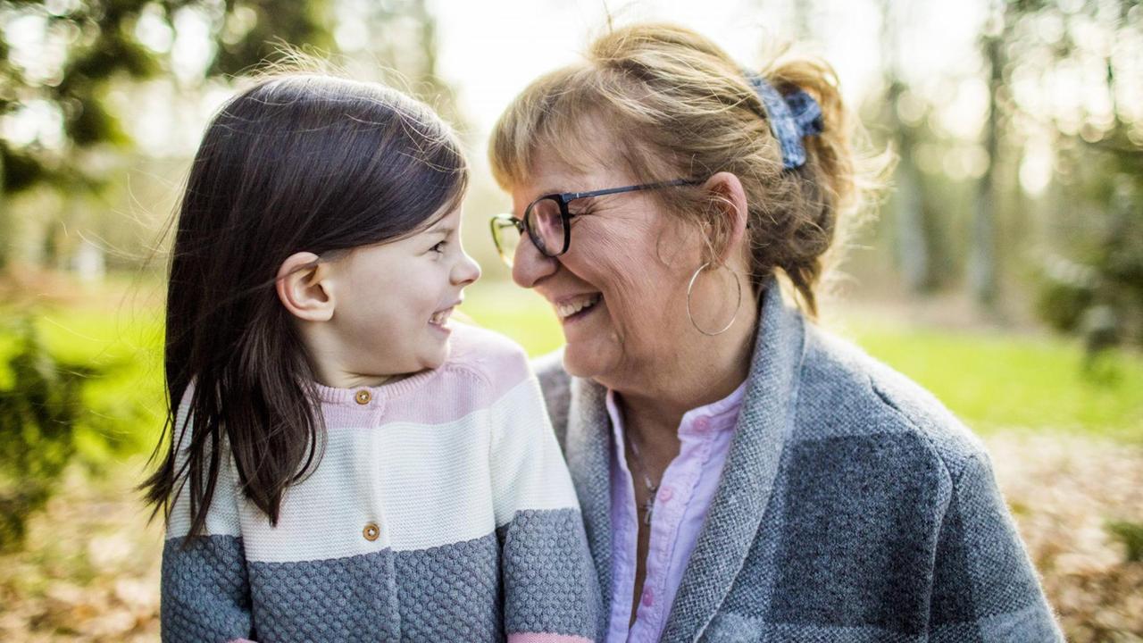 Großmutter und Enkelin lachen sich an draußen im Garten. Großmutter und Enkelin lachen sich an draußen im Garten.