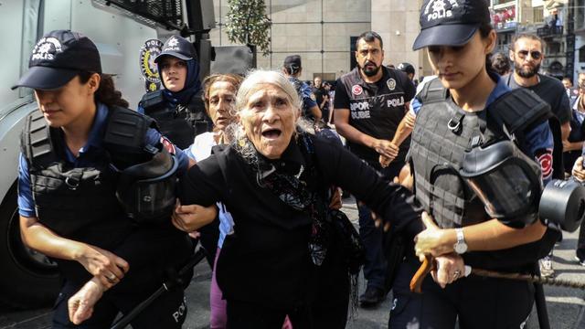 Eine alte Frau wird von Polizistinnen abgeführt.
