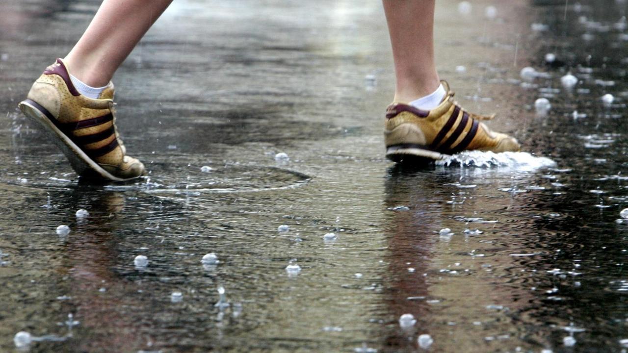 Die Schuhe einer Fußgängerin auf einer regennassen Straße in der Innenstadt von Frankfurt. Die Schuhe einer Fußgängerin auf einer regennassen Straße in der Innenstadt von Frankfurt.