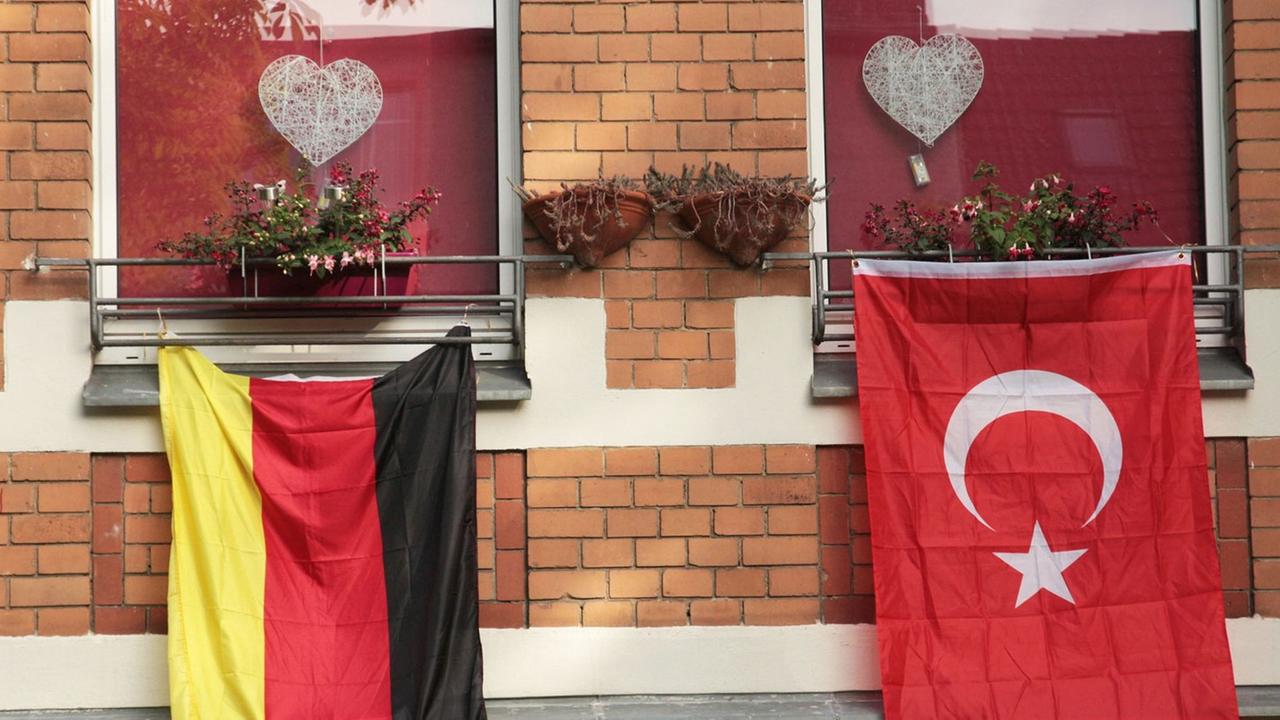 Eine rote, türkische Fahne mit dem Halbmond und dem Stern hängt während der Fußball-EM 2016 in Berlin an einem Haus neben der deutschen Flagge in Schwarz-Rot-Gold. Eine rote, türkische Fahne mit dem Halbmond und dem Stern hängt während der Fußball-EM 2016 in Berlin an einem Haus neben der deutschen Flagge in Schwarz-Rot-Gold.