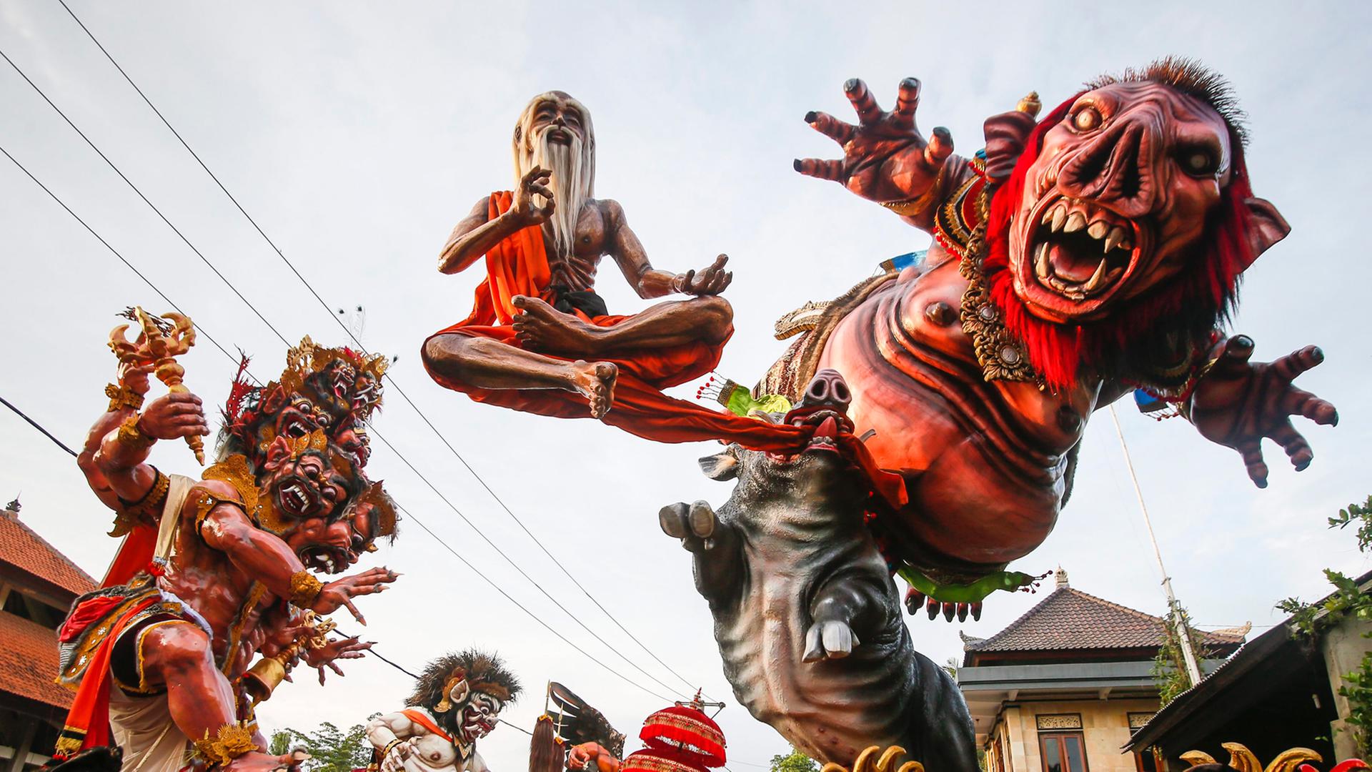 Rote monsterähnliche Figuren werden auf einer Parade von Männern in grünen T-Shirts getragen Rote monsterähnliche Figuren werden auf einer Parade von Männern in grünen T-Shirts getragen