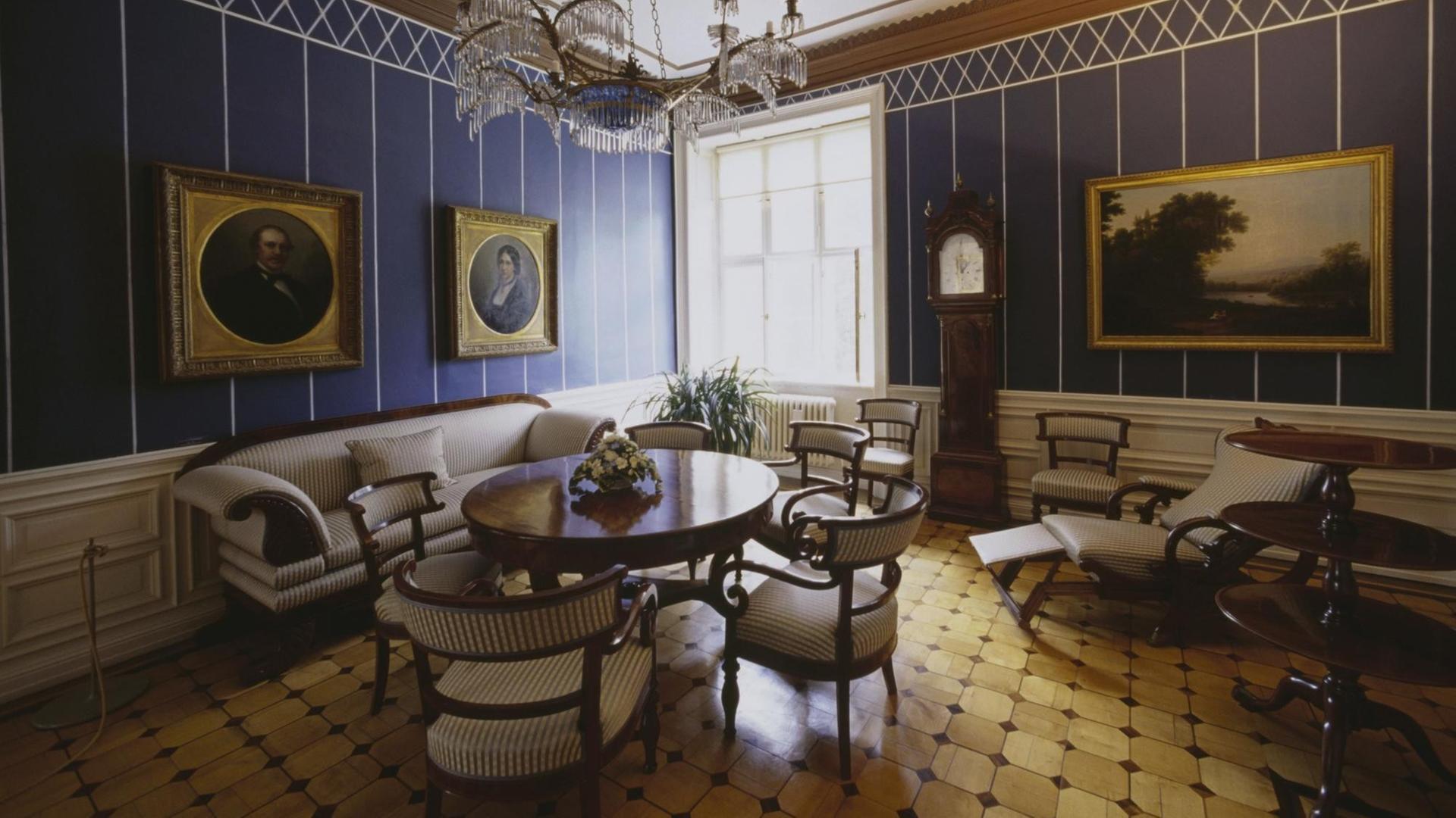 Blick in ein Wohnzimmer mit blauen Wänden und Parkettboden. Blick in ein Wohnzimmer mit blauen Wänden und Parkettboden.