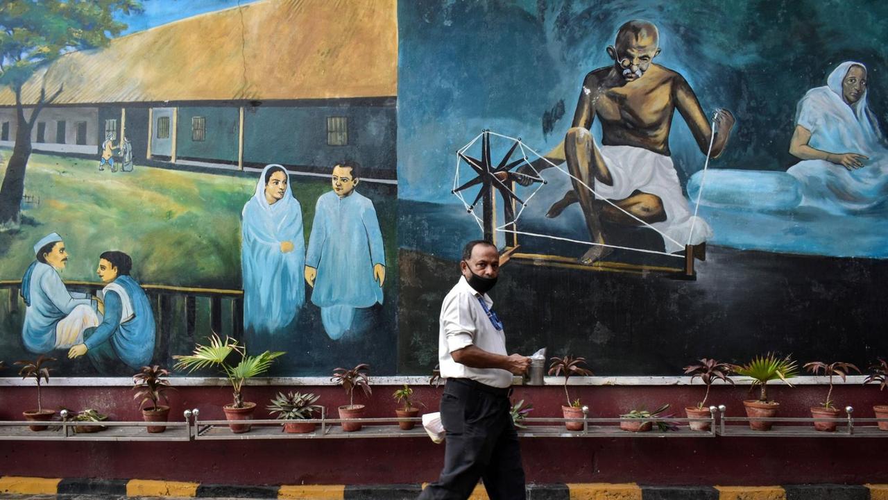 An einem Gebäude ist ein Bild von Gandhi gemalt, ein Mann geht daran vorbei. An einem Gebäude ist ein Bild von Gandhi gemalt, ein Mann geht daran vorbei.