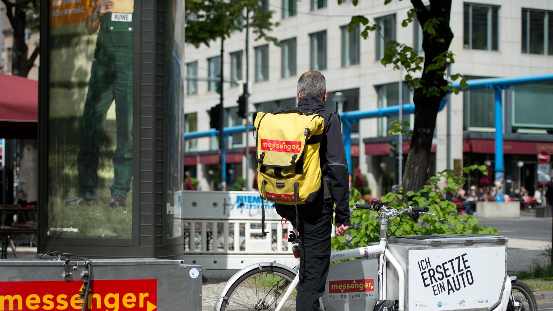 Ein Kurierfahrer mit einem Lastenfahrrad wartet in Berlin an einer Ampel auf die Weiterfahrt. Ein Kurierfahrer mit einem Lastenfahrrad wartet in Berlin an einer Ampel auf die Weiterfahrt.