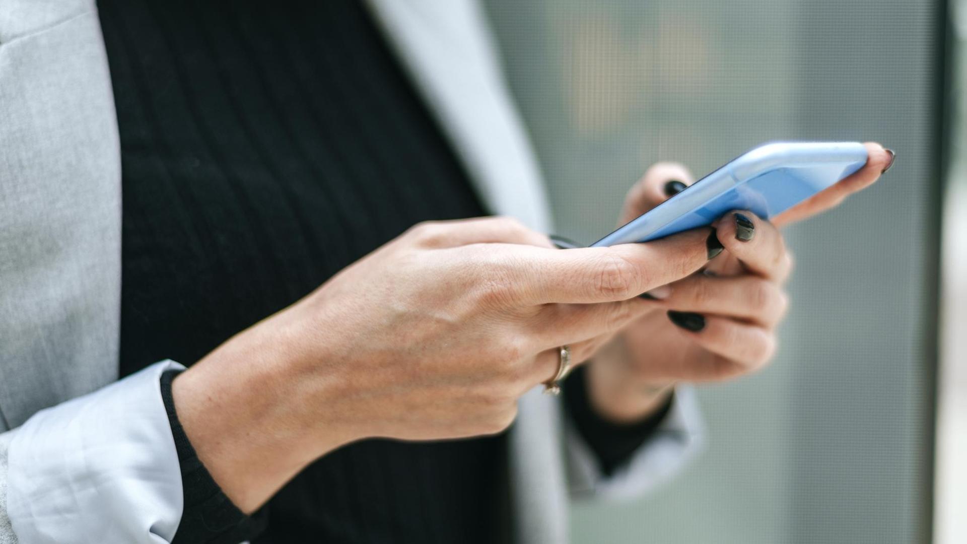 Eine Frau hält ein Smartphone in den Händen Eine Frau hält ein Smartphone in den Händen