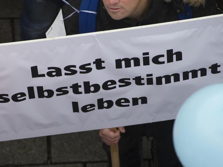 "Lasst mich selbstbestimmt leben" steht am 07.11.2016 in Berlin auf dem Plakat eines Demonstranten vor dem Brandenburger Tor. Die Bundesvereinigung "Lebenshilfe" hatte zu einer Demonstration aufgerufen, um ein besseres Bundesteilhabegesetz (BTHG) für Menschen mit Behinderung zu fordern. Derzeit befassen sich bundespolitische Gremien mit der künftigen Gestaltung des neuen BTHG. Foto: Paul Zinken/dpa ++