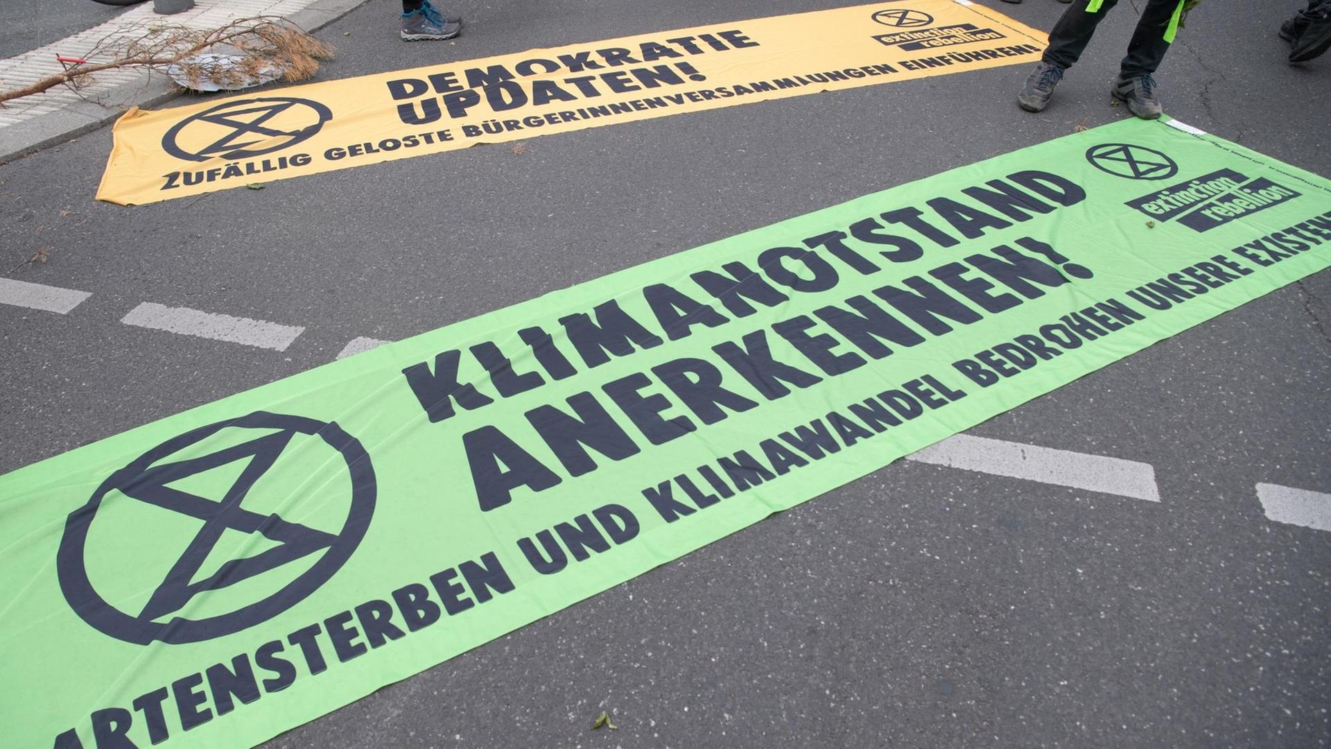 Transparente mit der Aufschrift "Klimanotstand anerkennen" (vorne) und "Demokratie updaten" liegen bei einer Demonstration unter dem Motto "Trauerzug der toten Bäume" von Extinction Rebellion (XR) unweit des Bundeslandwirtschaftsministeriums auf dem Boden. Transparente mit der Aufschrift "Klimanotstand anerkennen" (vorne) und "Demokratie updaten" liegen bei einer Demonstration unter dem Motto "Trauerzug der toten Bäume" von Extinction Rebellion (XR) unweit des Bundeslandwirtschaftsministeriums auf dem Boden.
