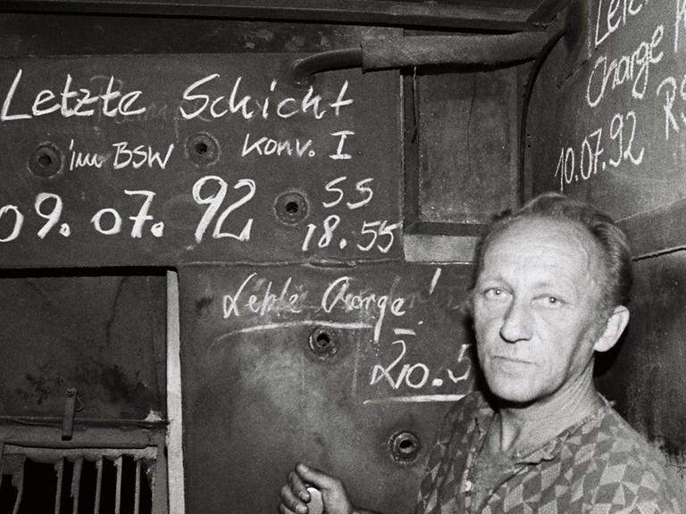 Ein Arbeiter blickt besorgt in die Kamera. Die schwarz-weiße Aufnahme ist entstanden im Stahl- und Walzwerk Maxhütte in Unterwellenborn, Thüringen, nach der letzten Schicht im Juli 1992.