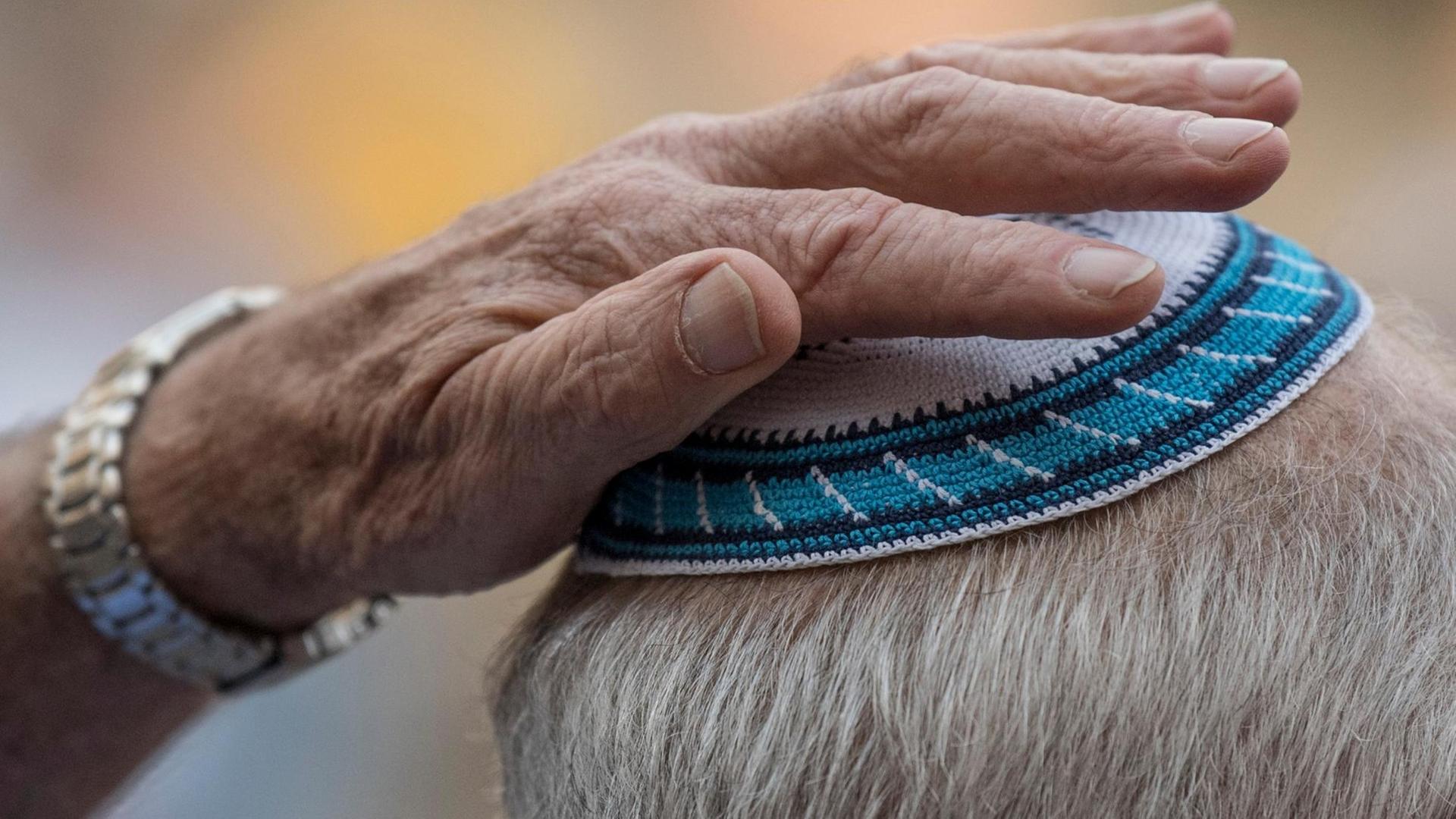Ein Mann setzt sich auf der Kundgebung zum "Kippa-Tag" auf dem Römerberg in Frankfurt seine Kippa auf Ein Mann setzt sich auf der Kundgebung zum "Kippa-Tag" auf dem Römerberg in Frankfurt seine Kippa auf