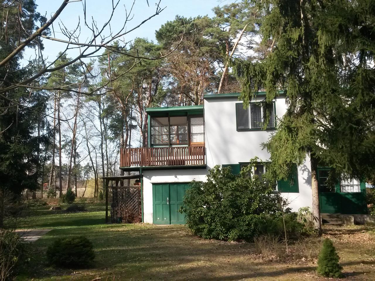 Weißes Haus mit grünen Türen und Holzbalkon in einem Garten Weißes Haus mit grünen Türen und Holzbalkon in einem Garten
