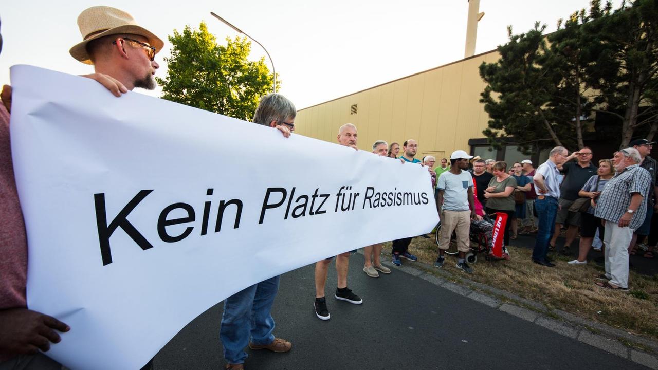 Menschen bei einer Mahnwache gegen Rassismus halten ein Plakat mit der Aufschrift "Kein Platz für Rassismus". Menschen bei einer Mahnwache gegen Rassismus halten ein Plakat mit der Aufschrift "Kein Platz für Rassismus".