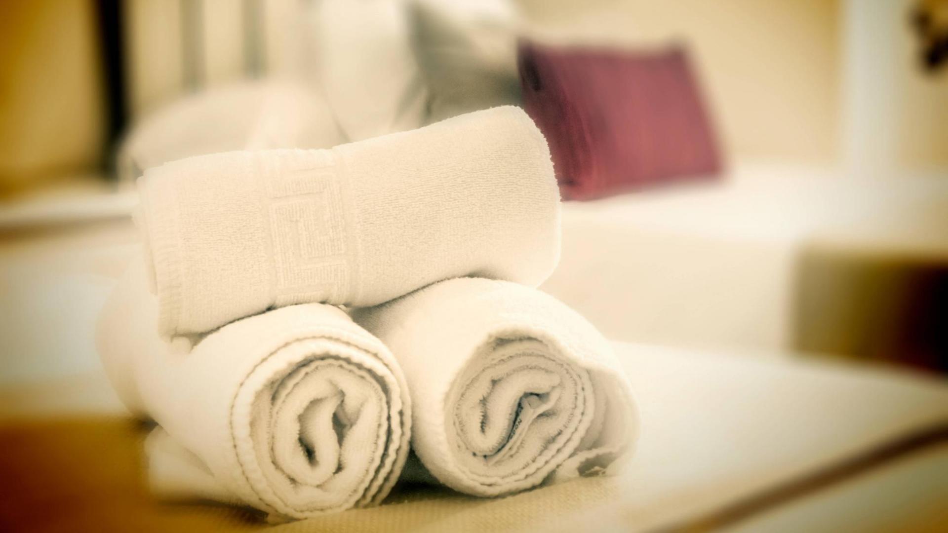 Saubere, gerollte Handtücher auf einem Bett bei Gegenlicht