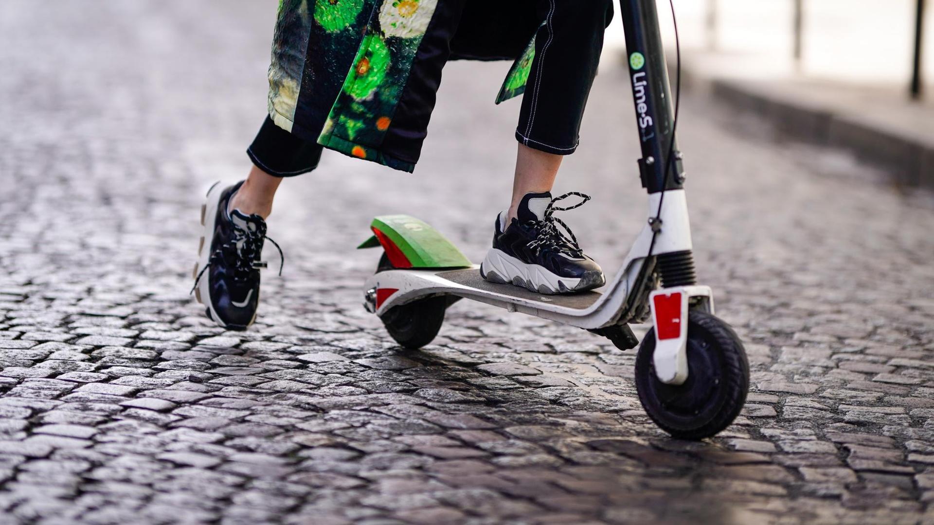 Detail einer Person die auf einem E-Tretroller fährt Detail einer Person die auf einem E-Tretroller fährt