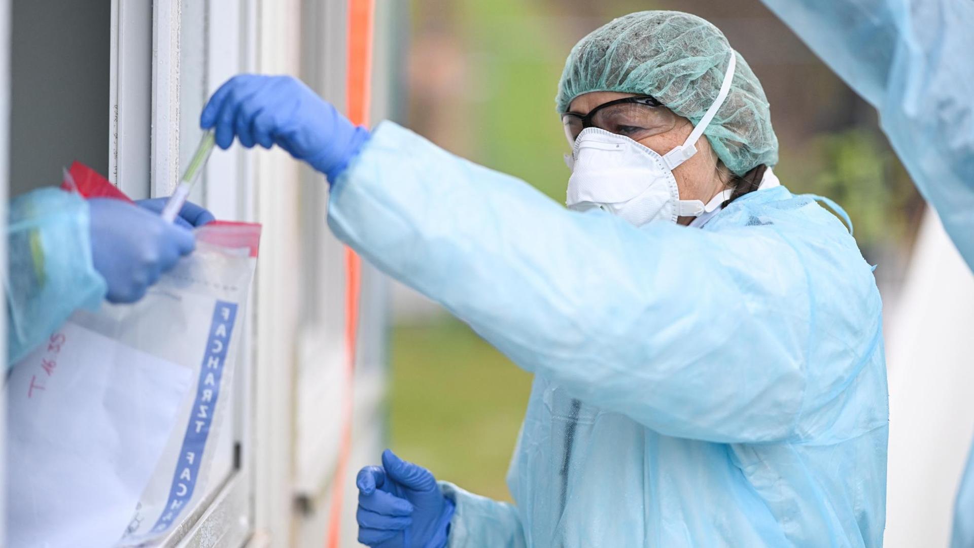 In einem Coronavirus-Testzentrum in Baden-Württemberg gibt eine Ärztin ein Abstrichstäbchen im Plastikröhrchen in einen Plastikbeutel.